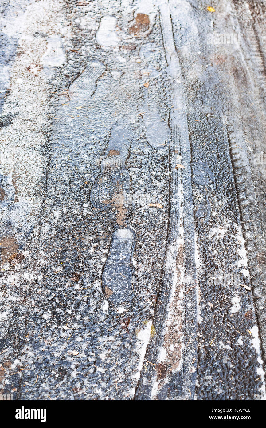 Gefrorene reifen Drucke und Spuren auf der Oberfläche des Eis verkrusteten Straße in kalten Herbst Tag Stockfoto