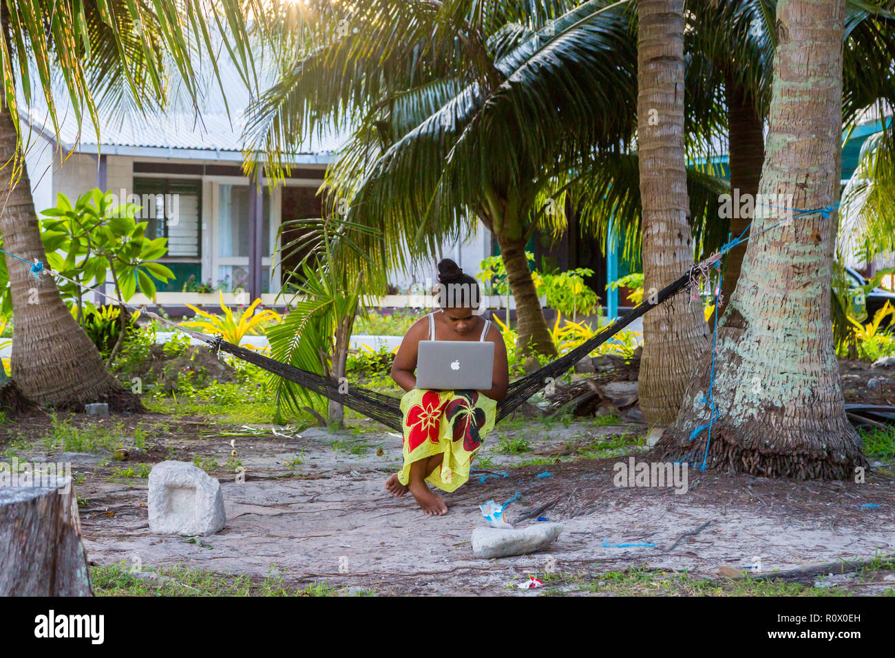 Vaiaku, Tuvalu - Dec 27, 2014: Junge polynesischen Frau in einer Hängematte mit einem Notebook arbeiten im Freien unter Palmen. Tuvalu, Polynesien, South Pacific Stockfoto