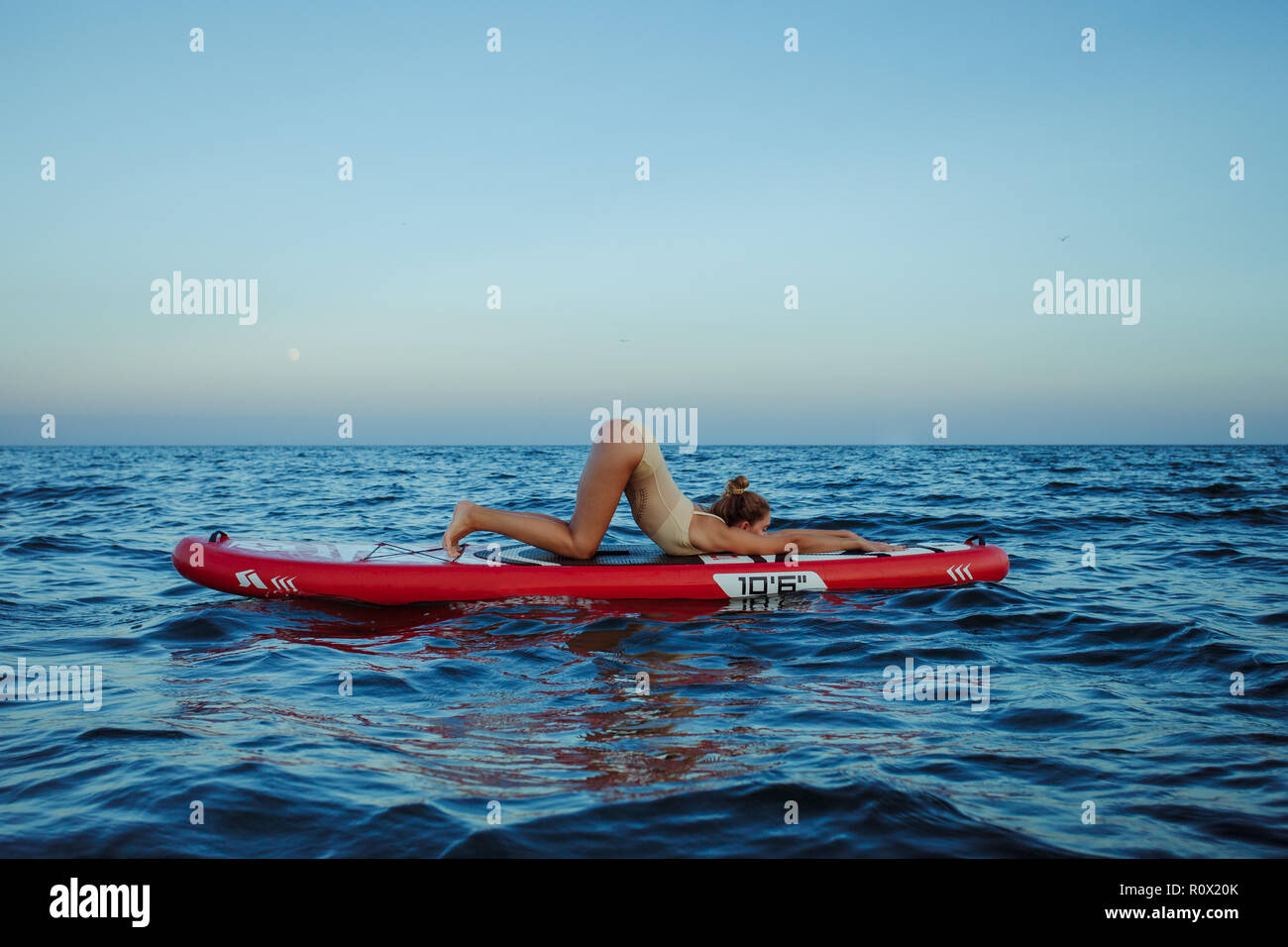Junge Frau Yoga ein SUP Board im Meer Stockfoto