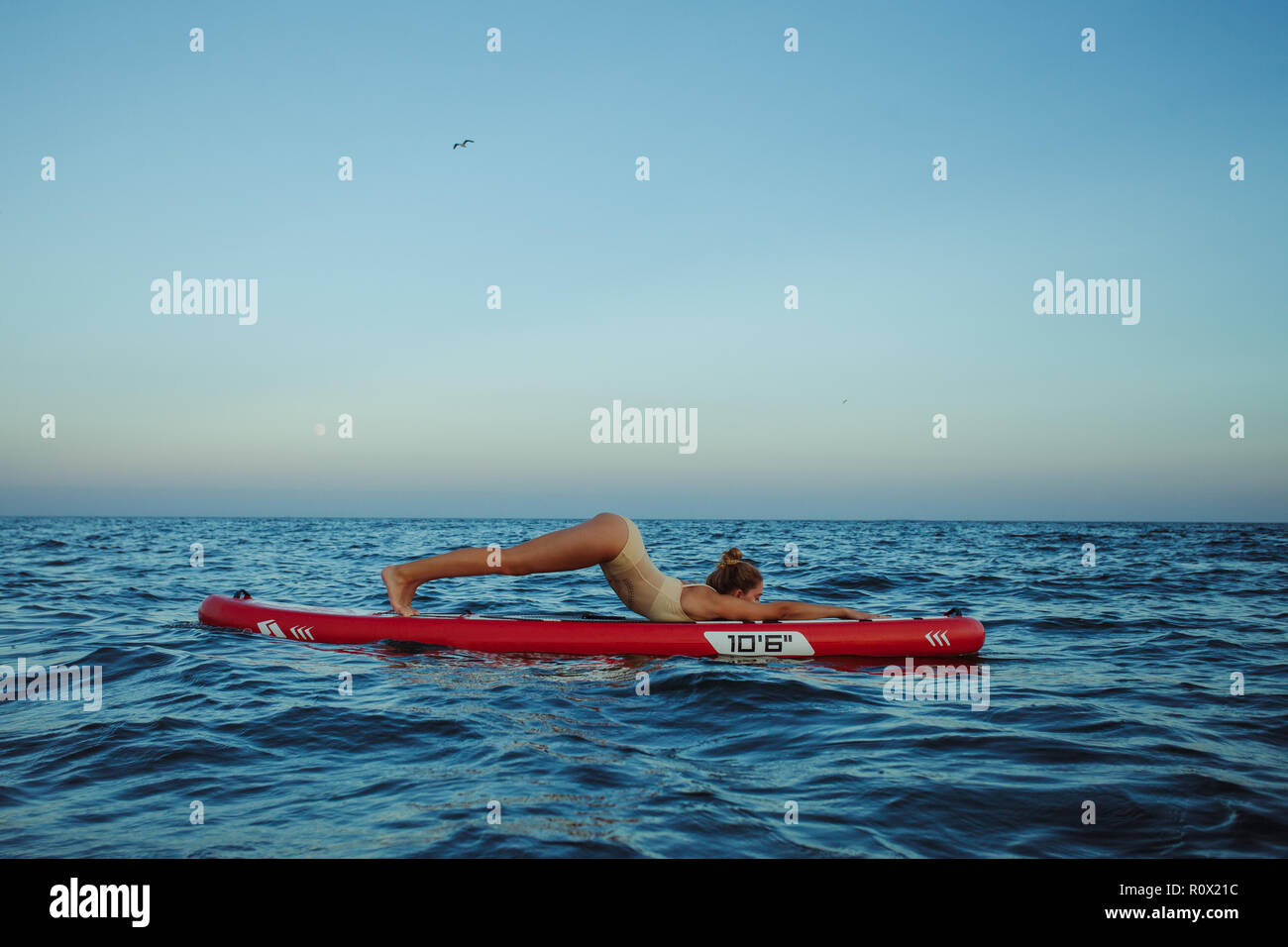 Junge Frau Yoga ein SUP Board im Meer Stockfoto