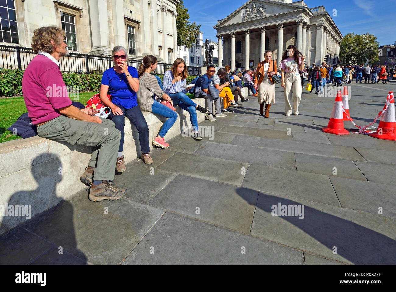 Menschen entspannend am Mittag vor der National Gallery am Trafalgar Square, London, England, UK. Stockfoto