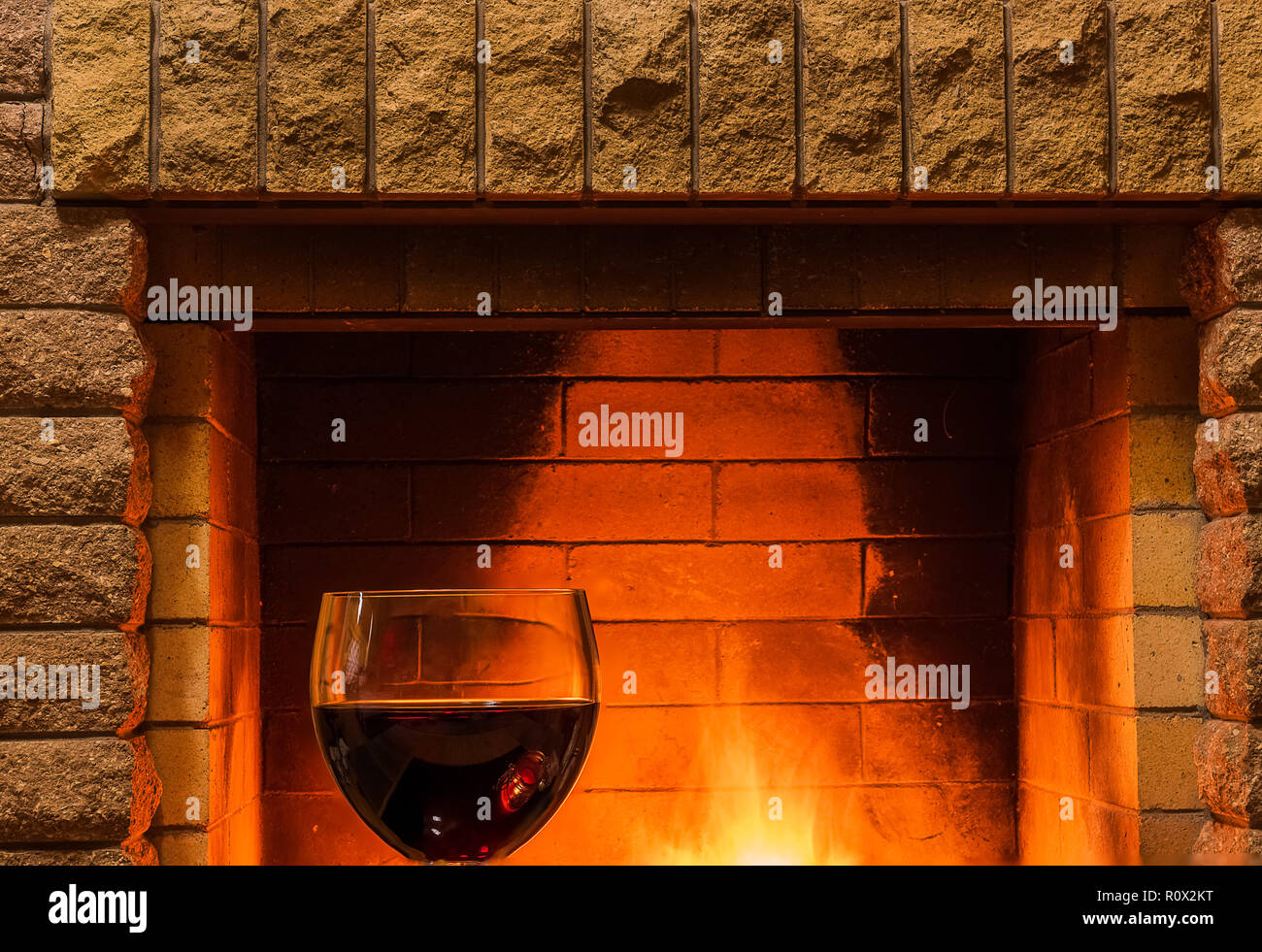 Ruhige Szene vor dem gemütlichen Kamin mit einem Glas Rotwein, im Landhaus, im Winter Urlaub. Stockfoto
