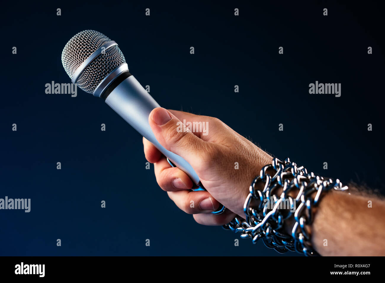 Die Freiheit der Presse und Journalismus, konzeptionelle Bild mit Mikrofon in männlicher Hand mit Ketten, Low Key Image gebunden Stockfoto