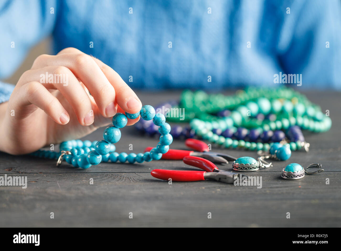 Herstellung von handgefertigten Schmuck. Kasten mit Perlen und Glas Herz auf alten hölzernen Hintergrund. Handmade Zubehör Stockfoto