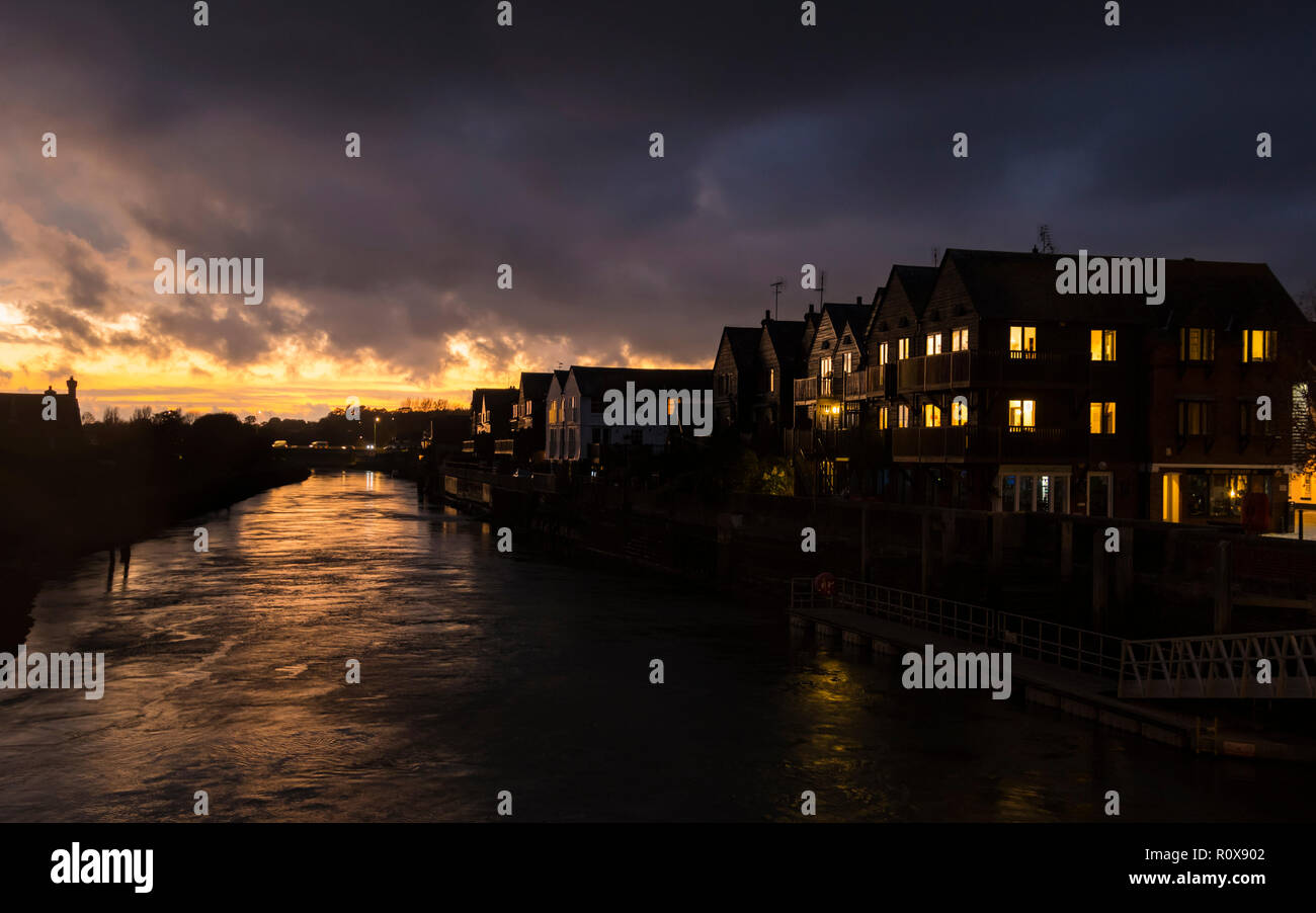 Sonne über dem Fluss Arun an einem bewölkten Herbst Abend mit feurigen Sonnenuntergang im Himmel in Arundel, West Sussex, England, UK. Riverside Gehäuse. Stockfoto