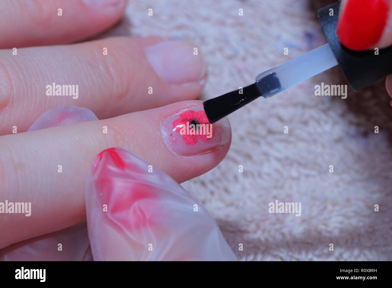 Nail Technician das Anwenden eines Mohn zu einem Fingernagel Tag der Erinnerung zu markieren. Stockfoto
