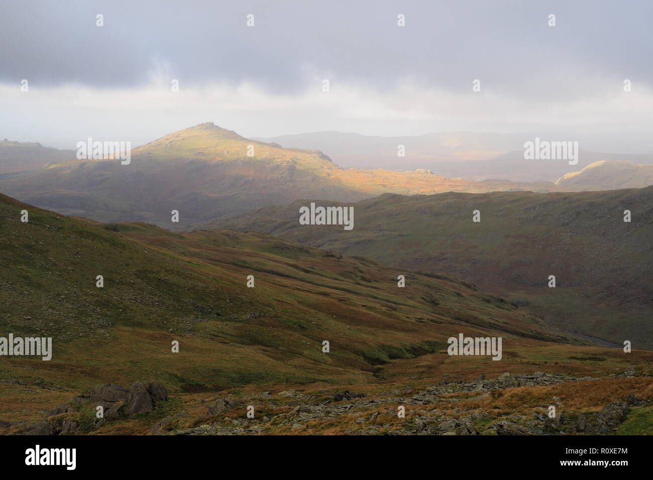 Sonnenlicht fällt auf einem See Bezirk Berg aus einem bewölkten und bewölkter Himmel es Beleuchtung mit warmen Herbstfarben Stockfoto