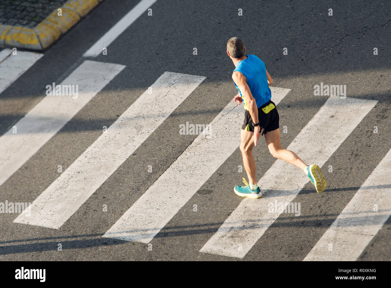 Athlet laufender Mann. Männliche Läufer vorbei an Zebrastreifen Stockfoto