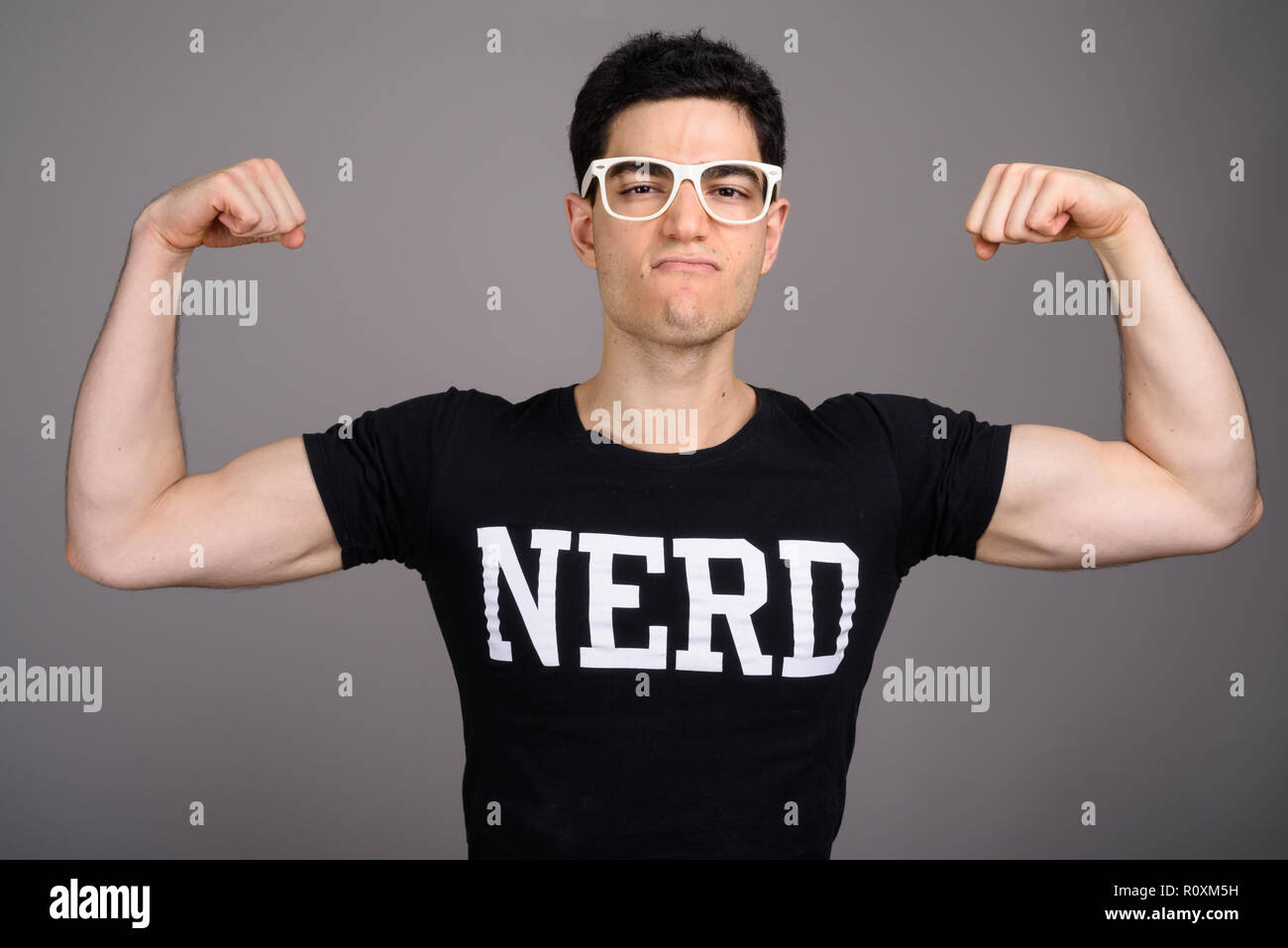 Junge schöne nerd Mann mit Brille gegen grauer Hintergrund Stockfoto