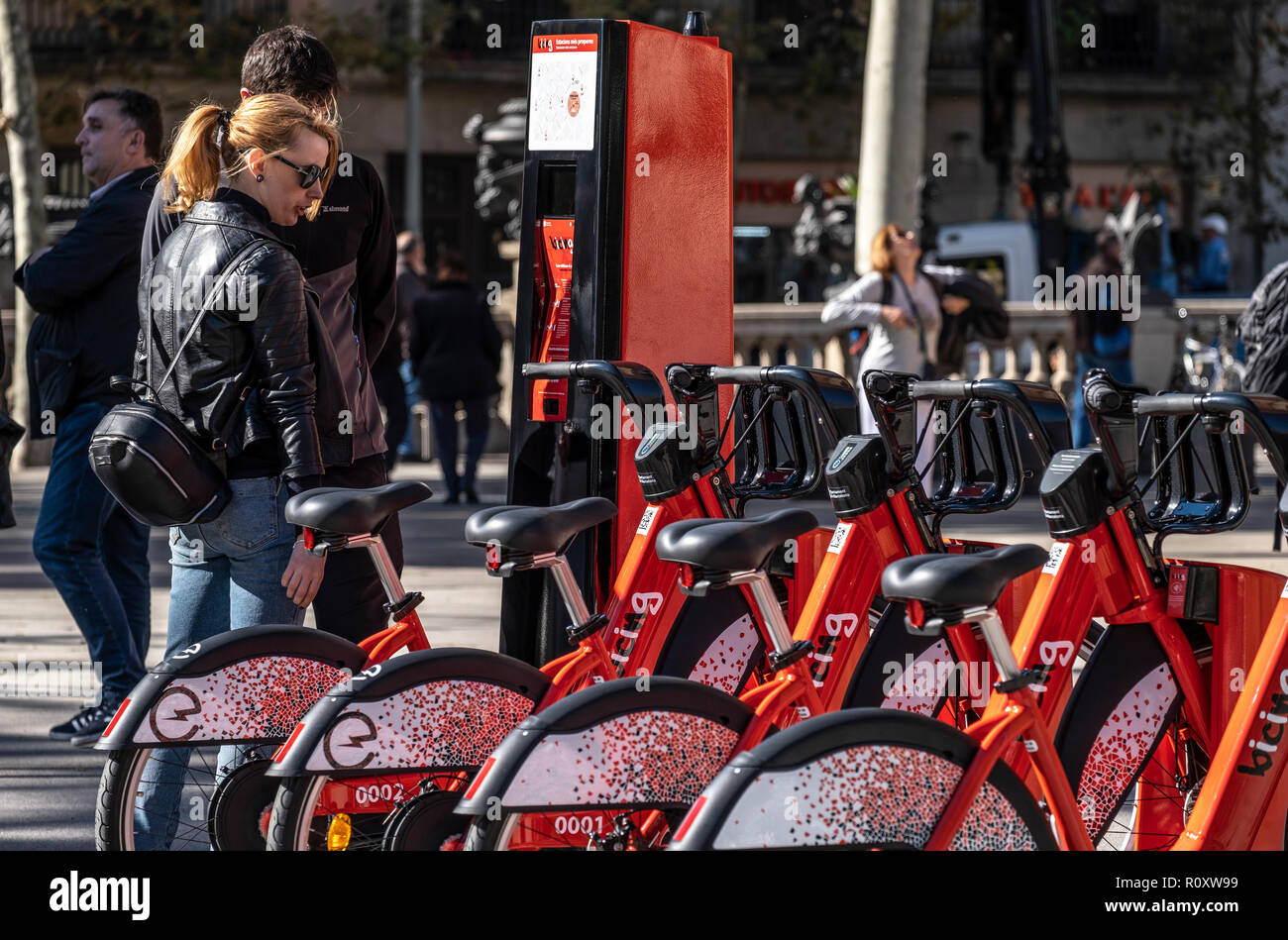 Zwei Touristen werden gesehen, beobachten das neue System der öffentlichen Fahrräder in Barcelona. Der Bürgermeister von Barcelona Ada Colau, begleitet von den Ratsherren Mercedes Vidal und Janet Sanz haben das neue Fahrrad Modelle, die im öffentlichen Dienst eines städtischen Fahrräder in Barcelona erneuern wird vorgestellt. Nach der Renovierung, Barcelonas öffentlichen Fahrradverleih Fahrräder zur Verfügung haben 7.000, von denen 1.000 elektrisch sein wird. Der Jahresbeitrag beträgt 50 Euro. Stockfoto
