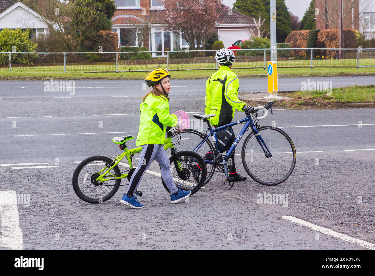 7. April 2018 Eine erschöpfte Mutter und Tochter mit ihren Zyklen über eine befahrene Kreuzung am Ballymaconnell Straße in Bangor Northern Ireland Stockfoto