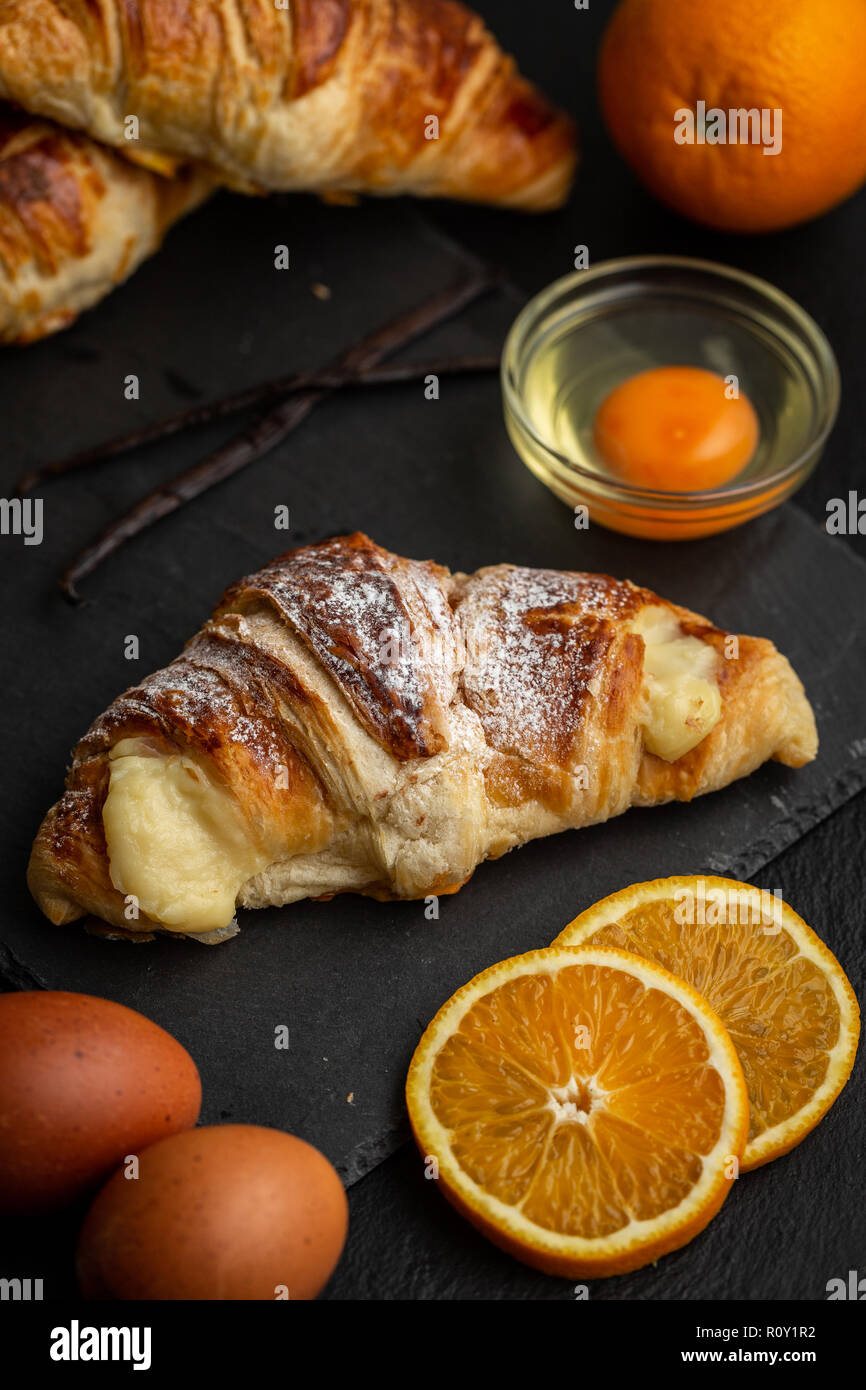 Croissants mit italienischen Vanillepudding mit Vanillesauce Zutaten: orange Scheiben, Eier und Vanilleschoten umgeben gefüllt Stockfoto