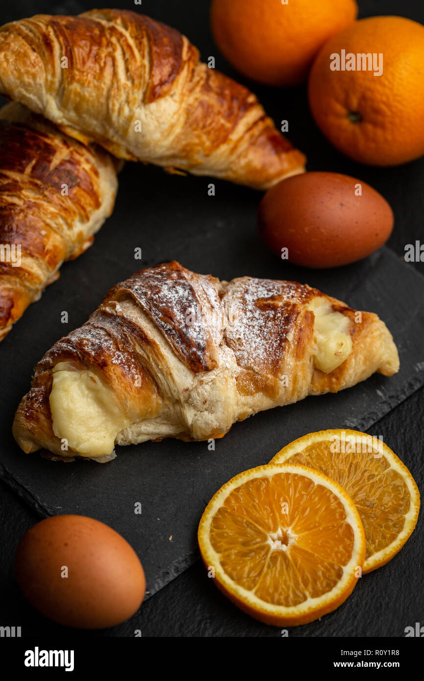 Croissants mit italienischen Vanillepudding mit Vanillesauce Zutaten: orange Scheiben, Eier und Vanilleschoten umgeben gefüllt Stockfoto