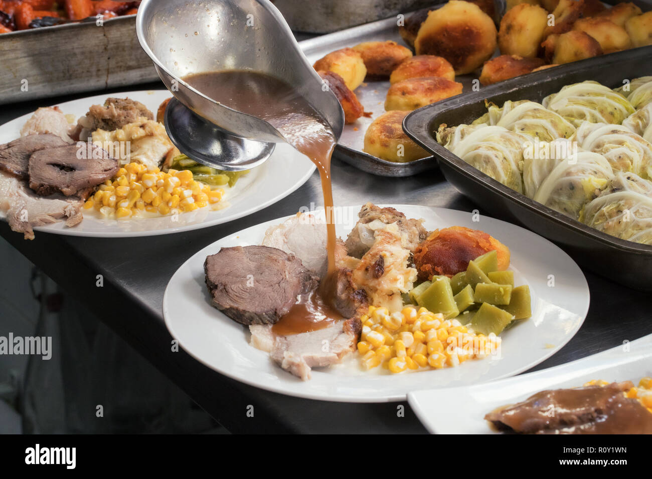 Sonntagsbraten Rind- und Schweinefleisch Abendessen mit Braten, Kartoffeln, Bohnen, Mais in Soße gegossen. Stockfoto