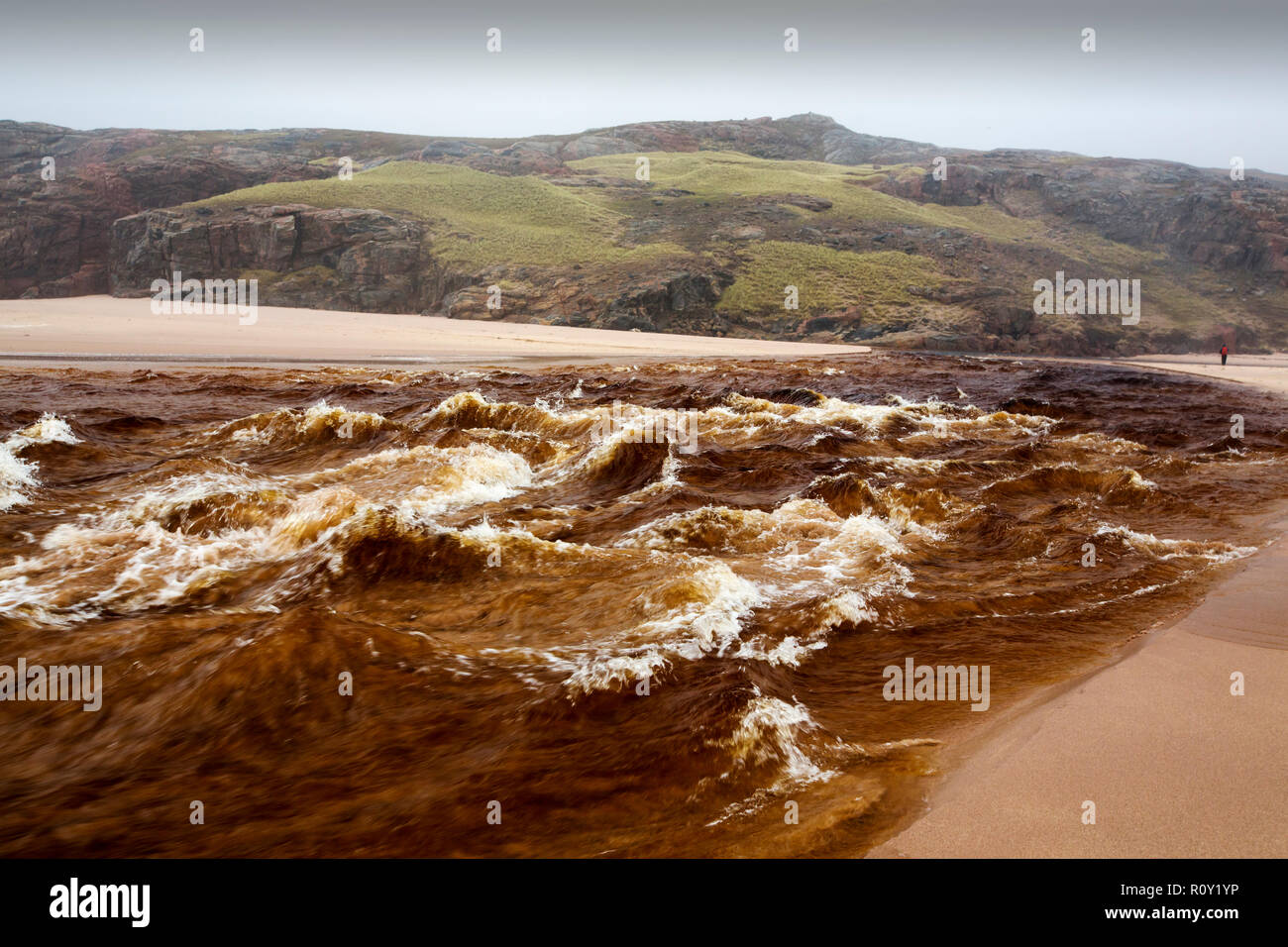 Der Abfluss von Sandwood Loch in der Flut Bedingungen über den Strand von Sandwood Bay, Sutherland, Schottland, Großbritannien, mit dem Wasser schwer befleckt durch Torf. Stockfoto