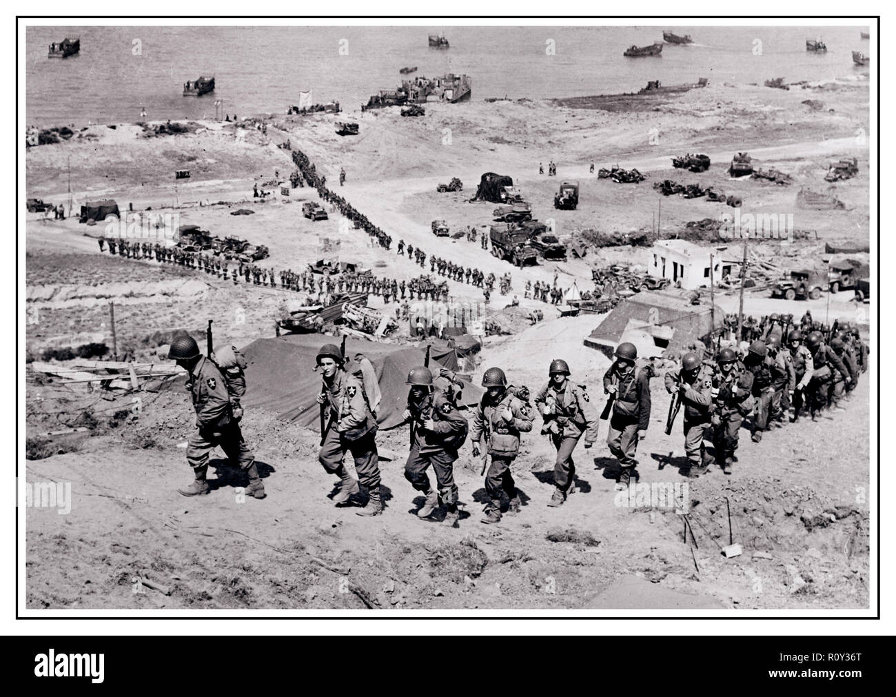 OPERATION OVERLORD D-Day+1 WW2 B&W Bild Der Aufbau am Omaha Beach in der Normandie. Usa 2 Infanterie Division Truppen und Ausrüstung landeinwärts in Richtung Saint-Laurent-sur-Mer am D-Day+1, 7. Juni 1944. Stockfoto