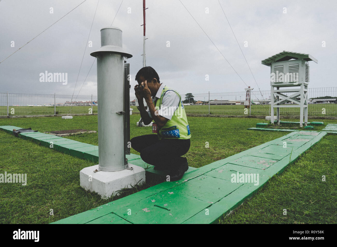 Meteorologe sieht die Regenmesser die Niederschlagsmenge im Internationalen Flughafen Ngurah Rai entfernt zu messen. Stockfoto