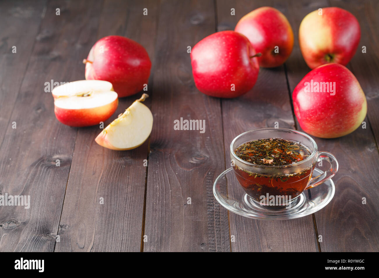 Kräutertee in Glas und Äpfel auf hölzernen Tisch Stockfoto