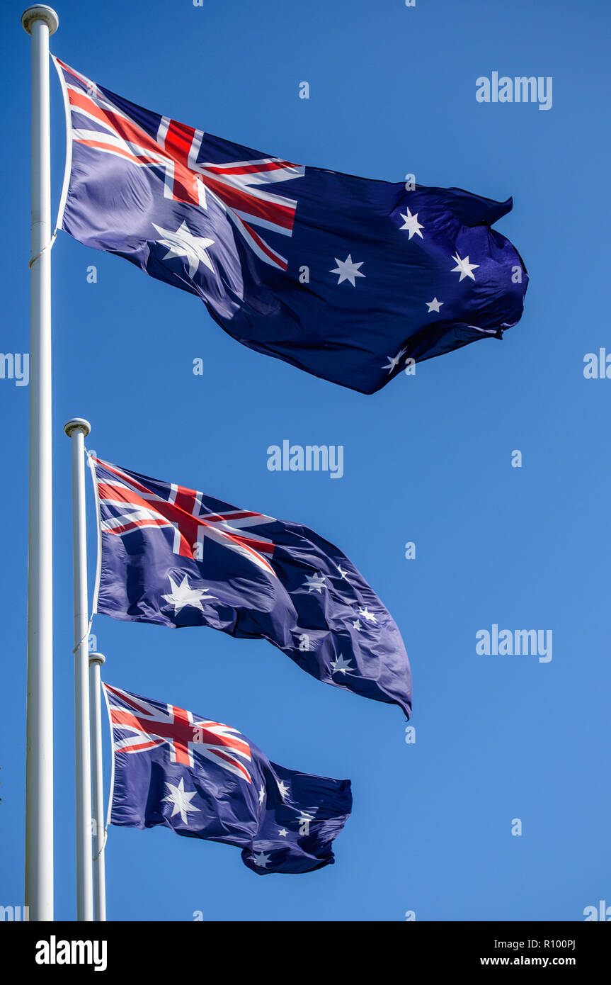 Drei australische nationale Flaggen jeder auf einem weißen Fahnenmast auf einem klaren blauen Himmel, Memorial Day. Stockfoto