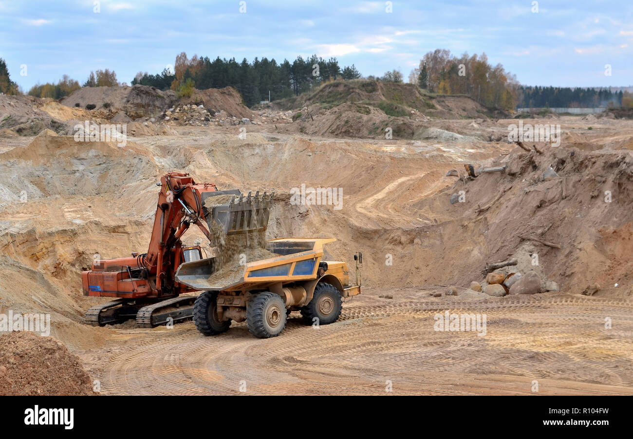 Großen Steinbruch Dump Truck. Angesichts der großen Sandkasten. Produktion nützliche Mineralien. Bergbau. Bagger laden Sand in die Kipper. Stockfoto