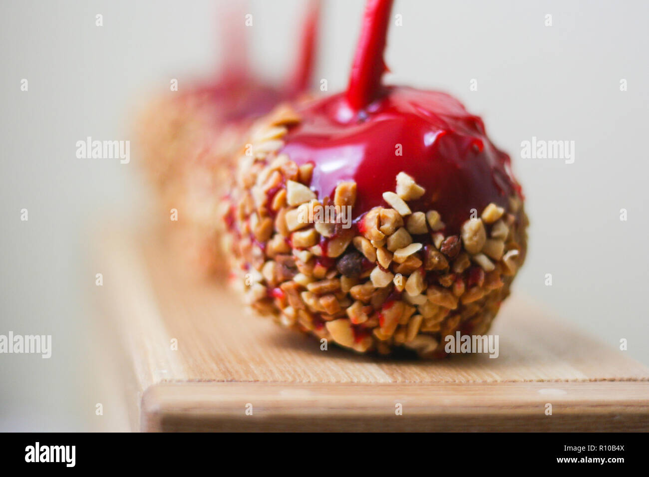 Drei helle rote candy Äpfel mit Muttern auf natürlichem Holz und grauer Hintergrund Stockfoto