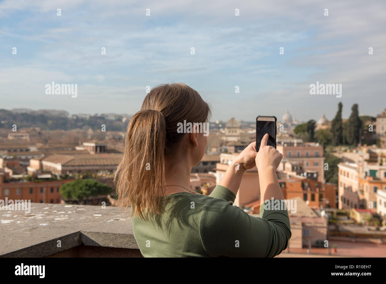 Mädchen in grüner Kleidung nimmt Fotos mit Smartphone in Rom, Italien Stockfoto