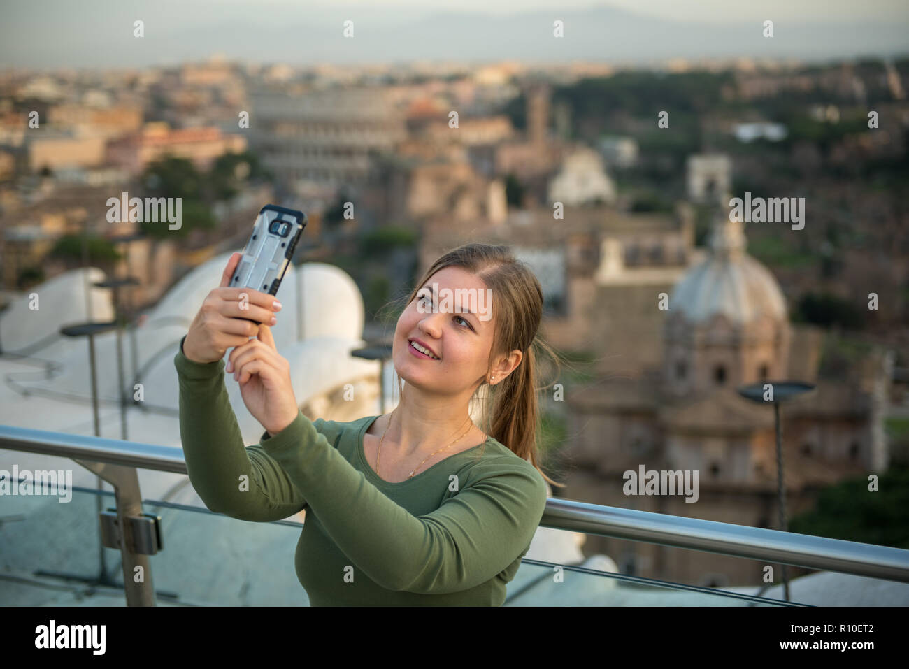 Junge Frau trägt grün Pullover auf dem Dach vor dem Kolosseum, Rom, Italien, macht selfie mit Ihrem Smartphone Stockfoto