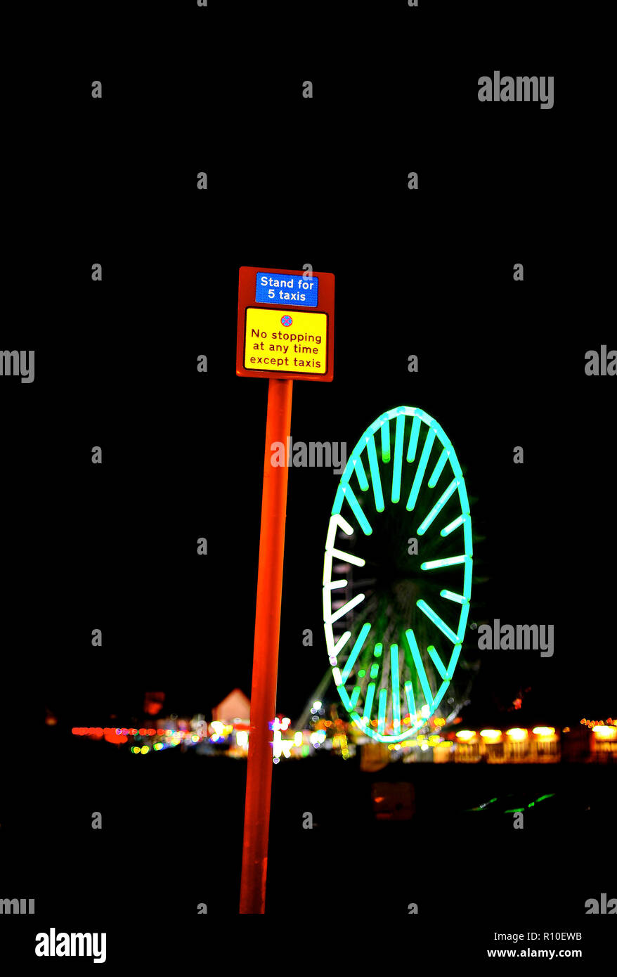 Schild mit Taxistand oben am Metallpfosten und Riesenrad am Central Pier nachts während der jährlichen Blackpool-Beleuchtung Stockfoto