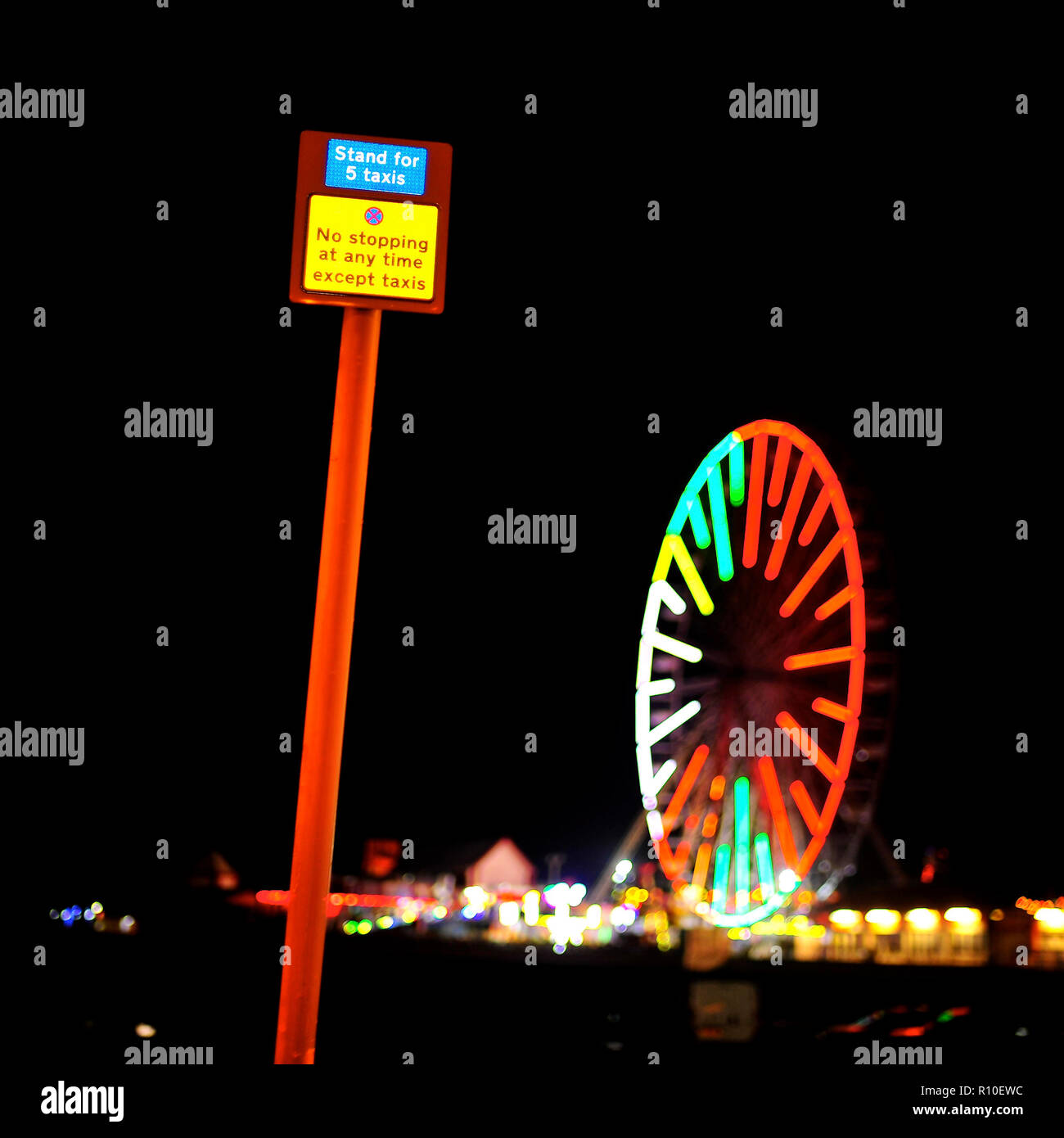 Schild mit Taxistand oben am Metallpfosten und Riesenrad am Central Pier nachts während der jährlichen Blackpool-Beleuchtung Stockfoto