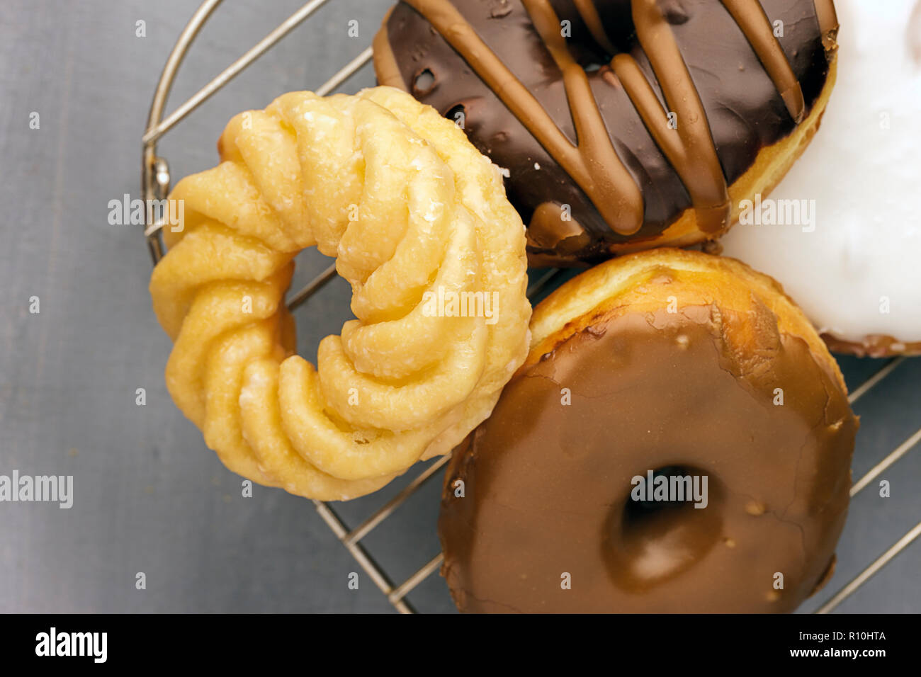 Ein Sortiment von verglast und mit Schokolade überzogene Donuts sitzen auf einem Gitter. Stockfoto