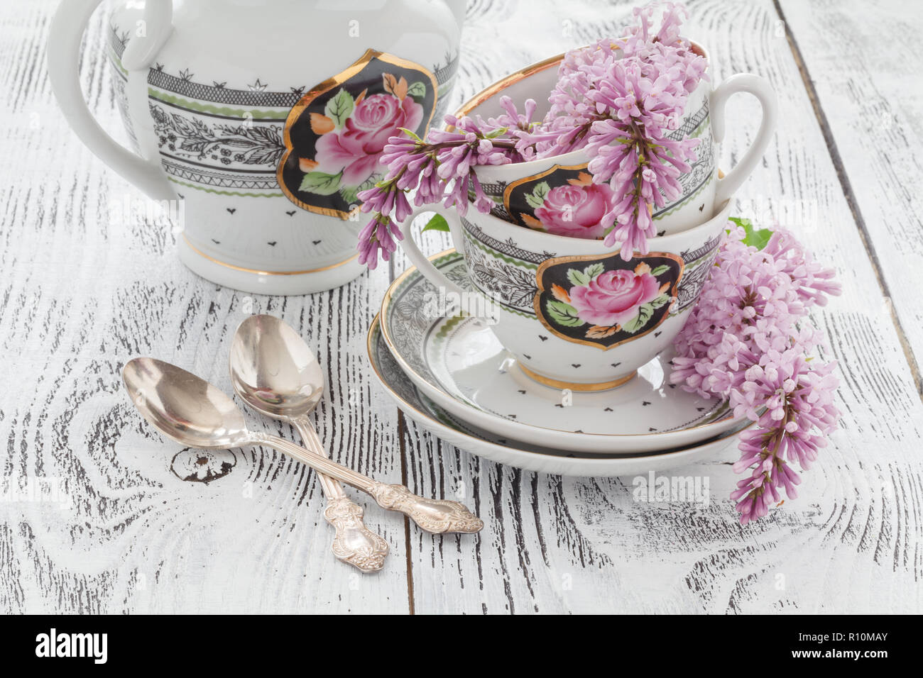 Filiale blühenden Flieder und Kaffee Tasse mit Milch auf einem Holztisch Stockfoto