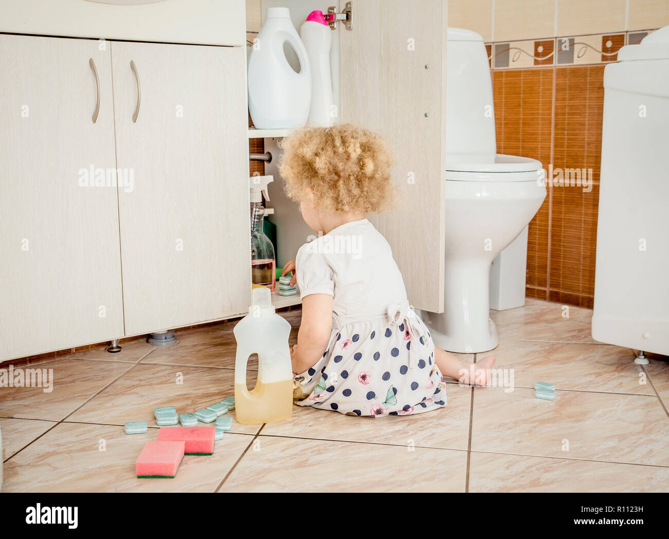 Unbeaufsichtigte Mädchen spielen in ruhige Lage, Bad mit gefährliche Haushaltschemikalien. Gefährdung der Sicherheit zu Hause Konzept. Fernhalten von der Kinder erreichen. Stockfoto