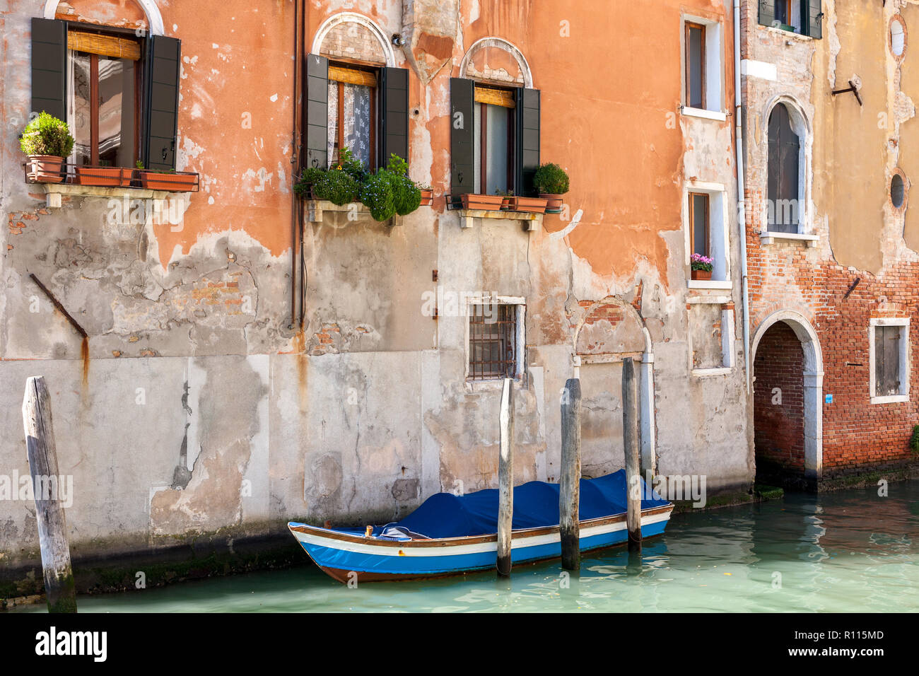 Blau bewaldeten Boot vor der alten Ziegel festgemacht und bemalte Gebäude Venedig Italien Stockfoto