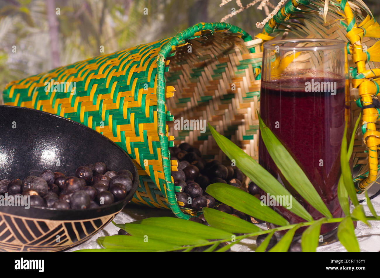 Acai Saft in ein Glas mit acai Beeren in einen Korb und ein acai Palme Wedel vor Stockfoto