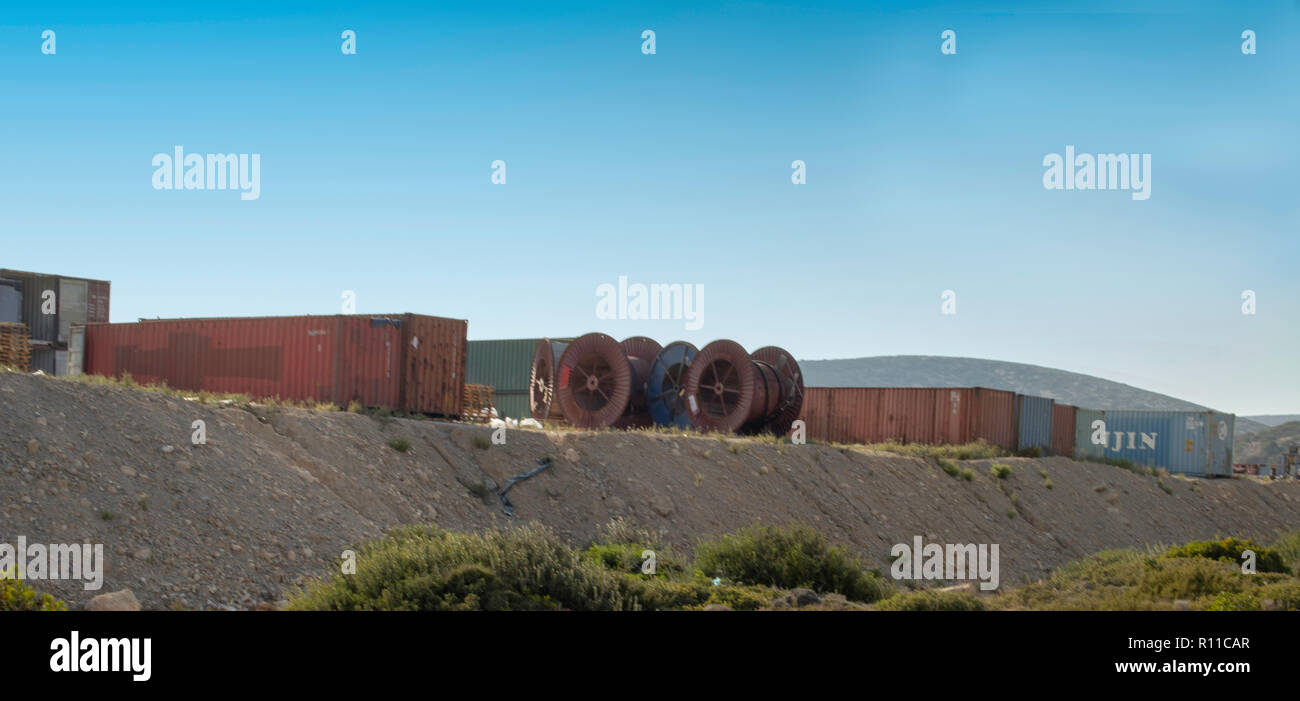 Alten Schiffscontainern und leeren großen Draht und Kabel Stahl reel spool Schlagzeug auf einem Hügel in der Nähe des Kraftwerks in Prasonisi, Rhodos, Griechenland, sich auszuruhen. Stockfoto