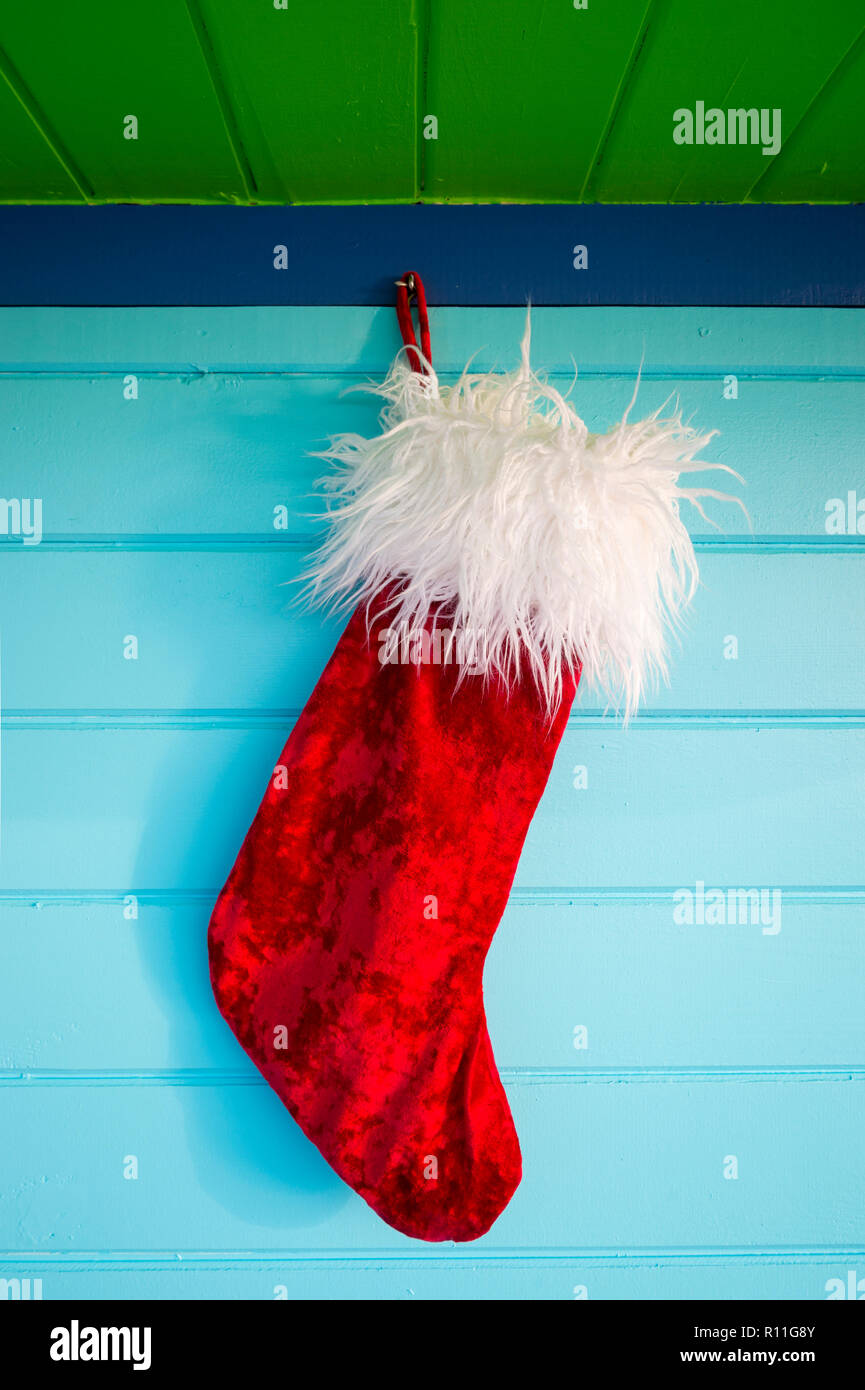 Plüsch red velvet Weihnachtsstrumpf hängen von rustikal Holz Hintergrund in tropischen Farben lackiert Stockfoto
