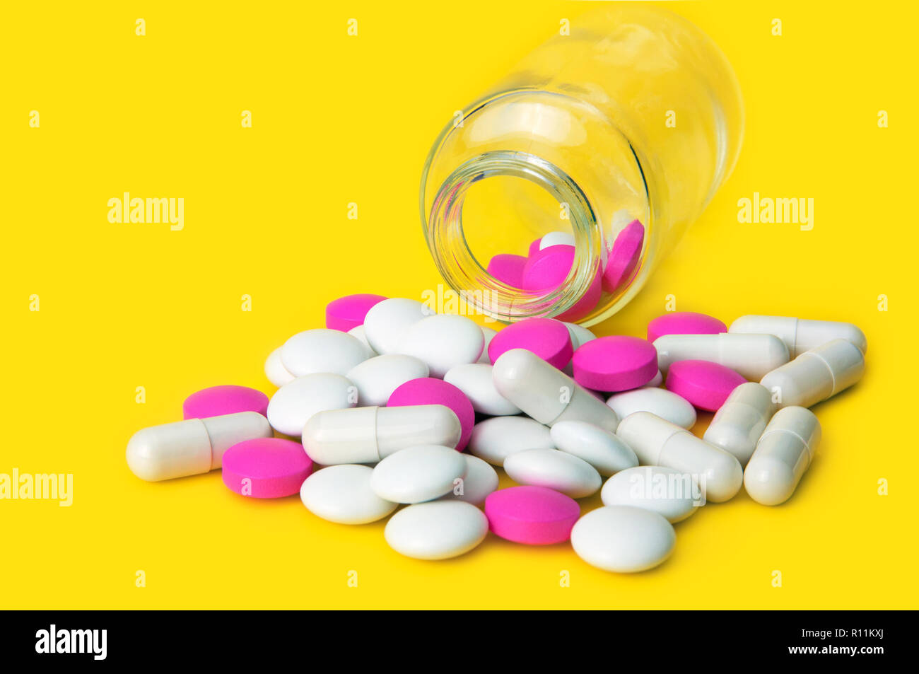Rosa und weissen Tabletten aus Glas auf einem gelben Hintergrund verstreut. Von der Seite. Stockfoto