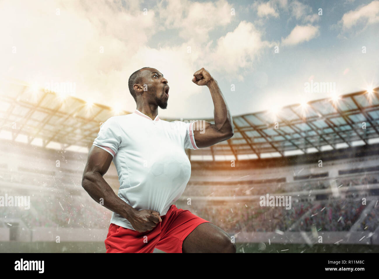 Die Fußball-afrikanische Spieler in Bewegung auf dem Gebiet der Stadion am Tag. Der professionelle Fußball, Fußball Spieler und menschlichen Emotionen Konzept. Der Gewinn, Gewinner, Sieg Konzept Stockfoto