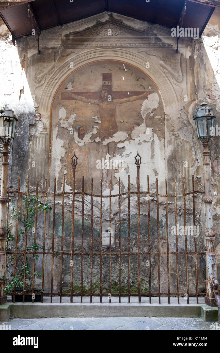 Ein Peeling alten Fresko auf einer Außenwand depicitng der Kreuzigung Christi wird durch die rostigen Eisengeländer, Lucca, Italien bewacht. Stockfoto