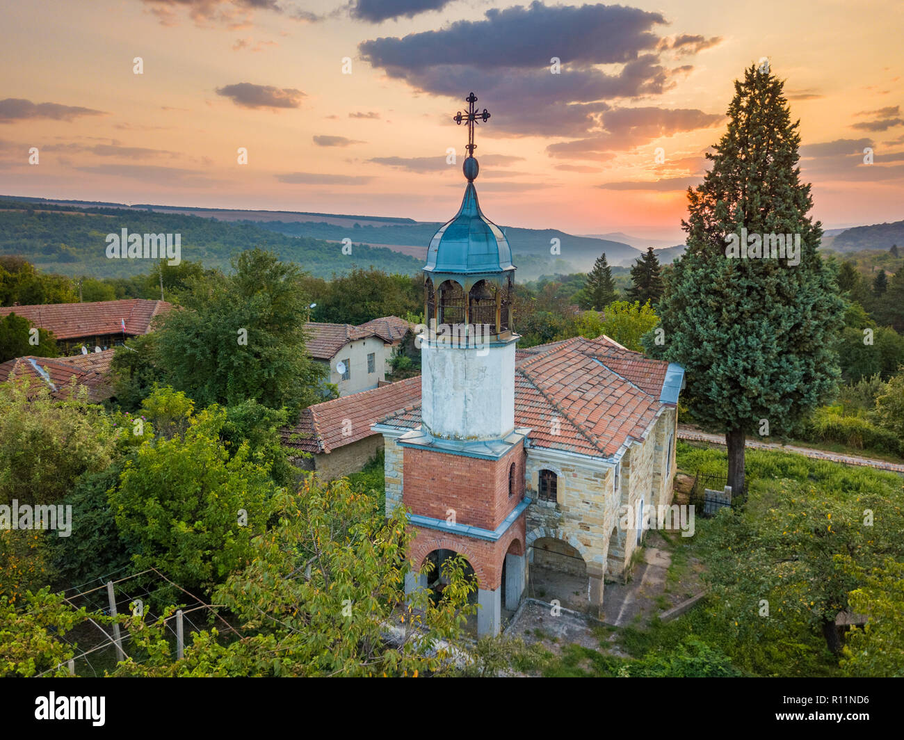 Luftaufnahmen von Eine kleine orthodoxe christliche Dorf im Norden von Bulgarien - kleine Kirche, typische Häuser - wunderschönen Sonnenaufgang in einer entspannten ländlichen Stockfoto