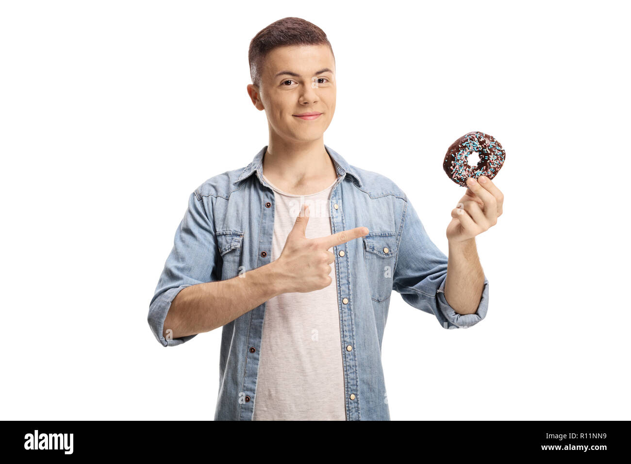 Junge Mann hält eine Schokolade Donut und zeigt auf weißem Hintergrund Stockfoto