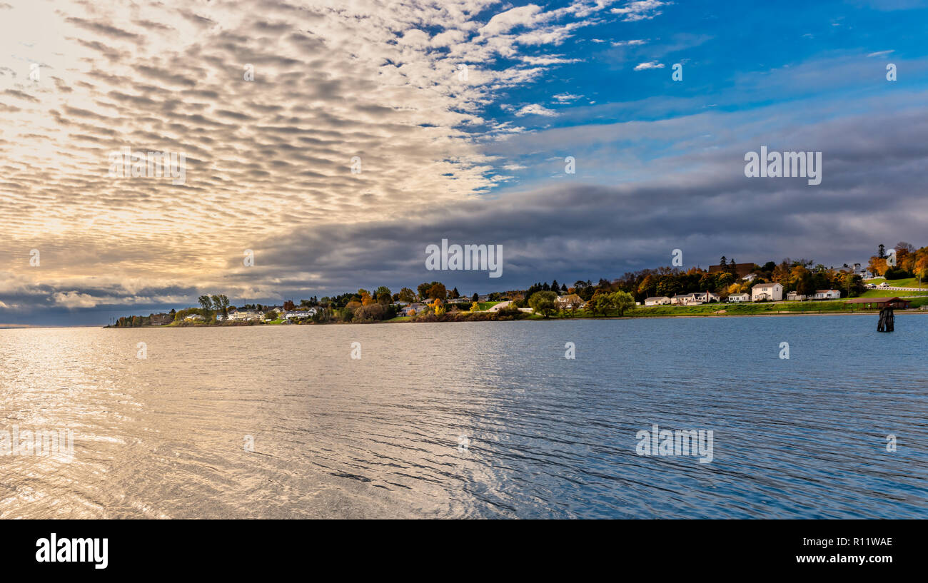 Panoramabild der Häuser am Seeufer mit Blick auf Lake Michigan während des Sonnenuntergangs. Von Wawatam Leuchtturm Geschossen Stockfoto