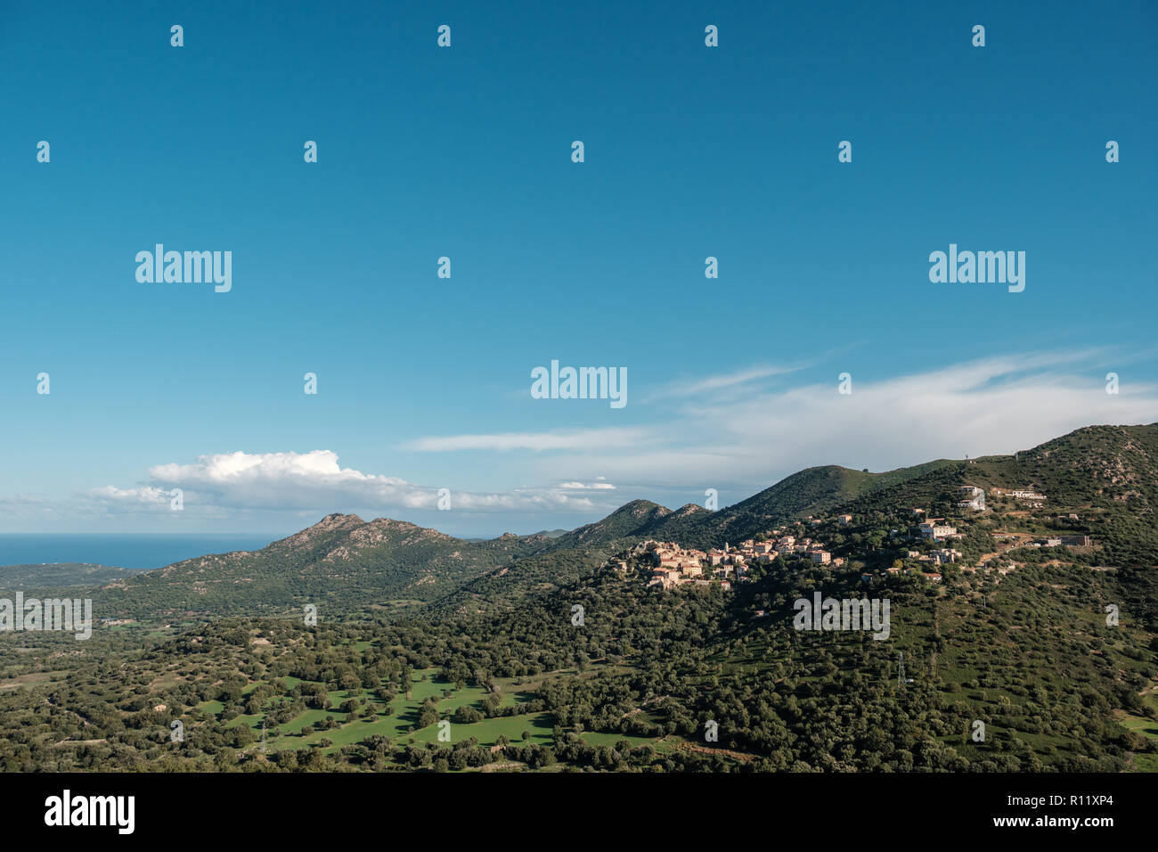 Am frühen Morgen die Sonne auf das Bergdorf Belgodere in der Balagne von Korsika mit Mittelmeer in der Ferne Stockfoto