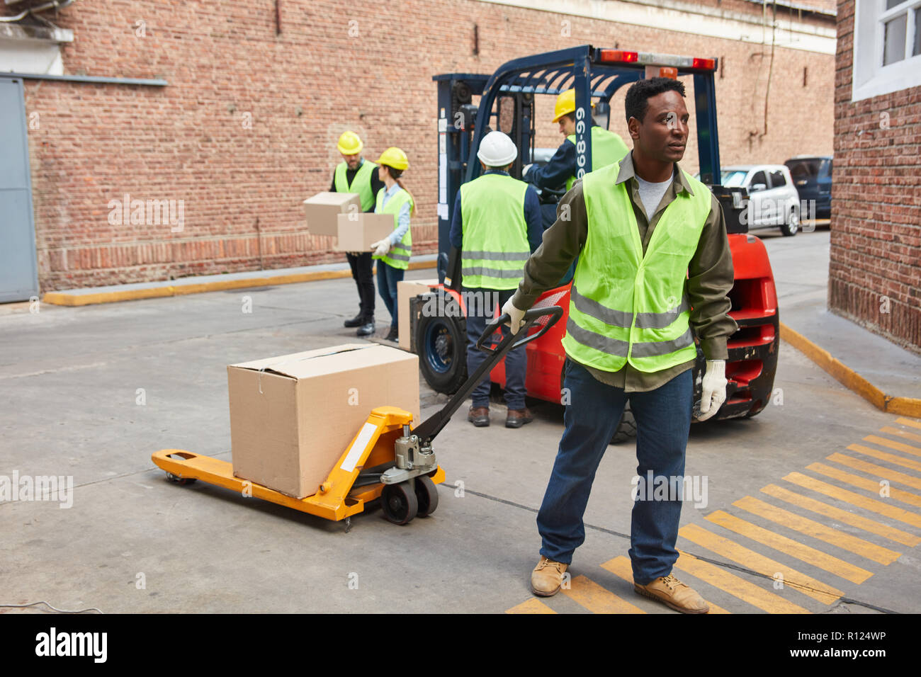 Afrikanische Arbeiter vor dem Logistikzentrum mit Paket auf der Palette Lkw Stockfoto