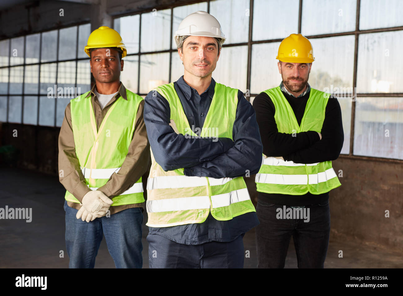 Drei zuversichtlich Logistik Arbeiter mit verschränkten Armen in der Halle Stockfoto