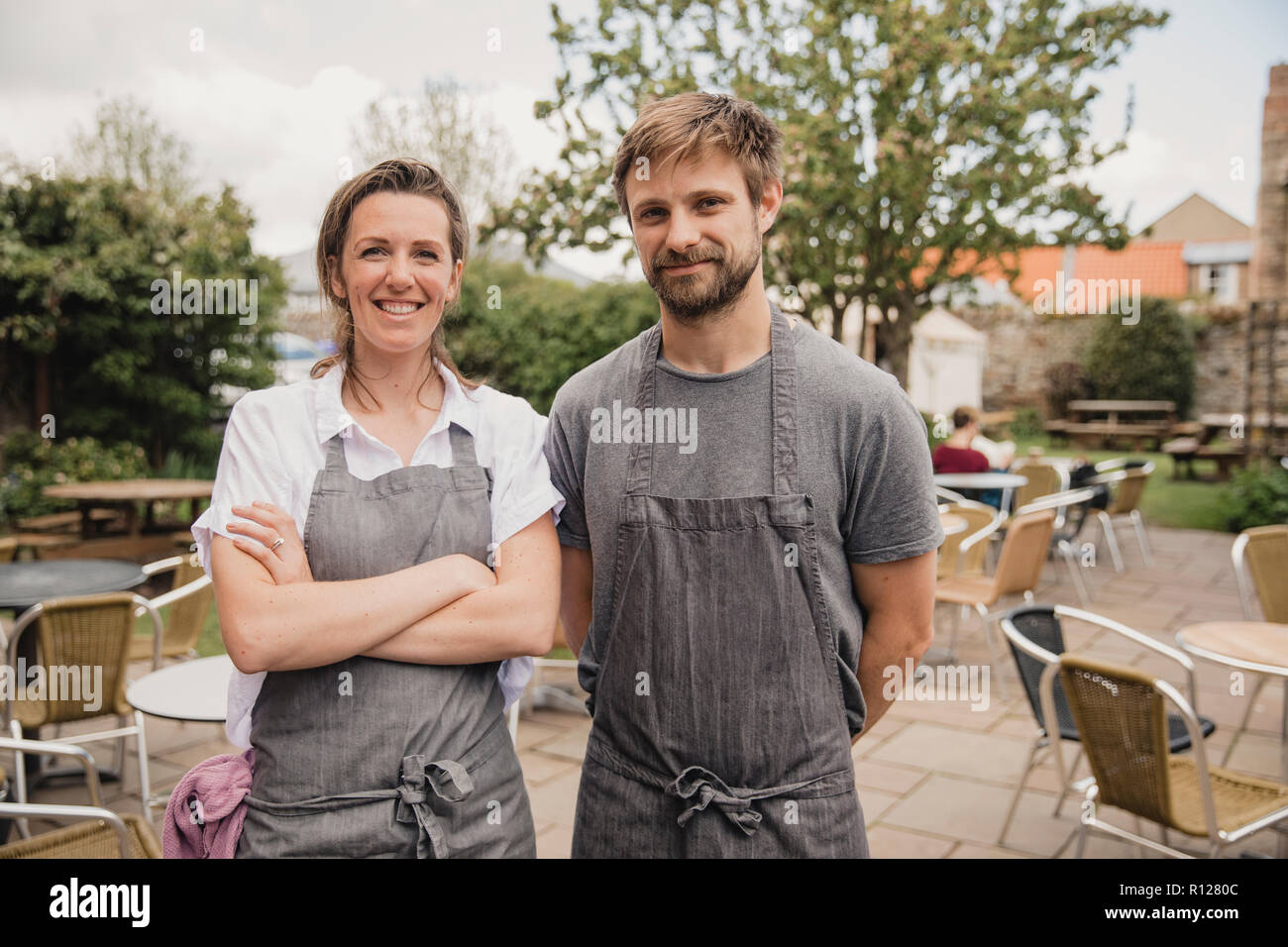 Portrait von zwei stolzen Coffee shop besitzer stehen vor der Sitzbereich im Freien an Ihrem kleinen Cafe. Stockfoto