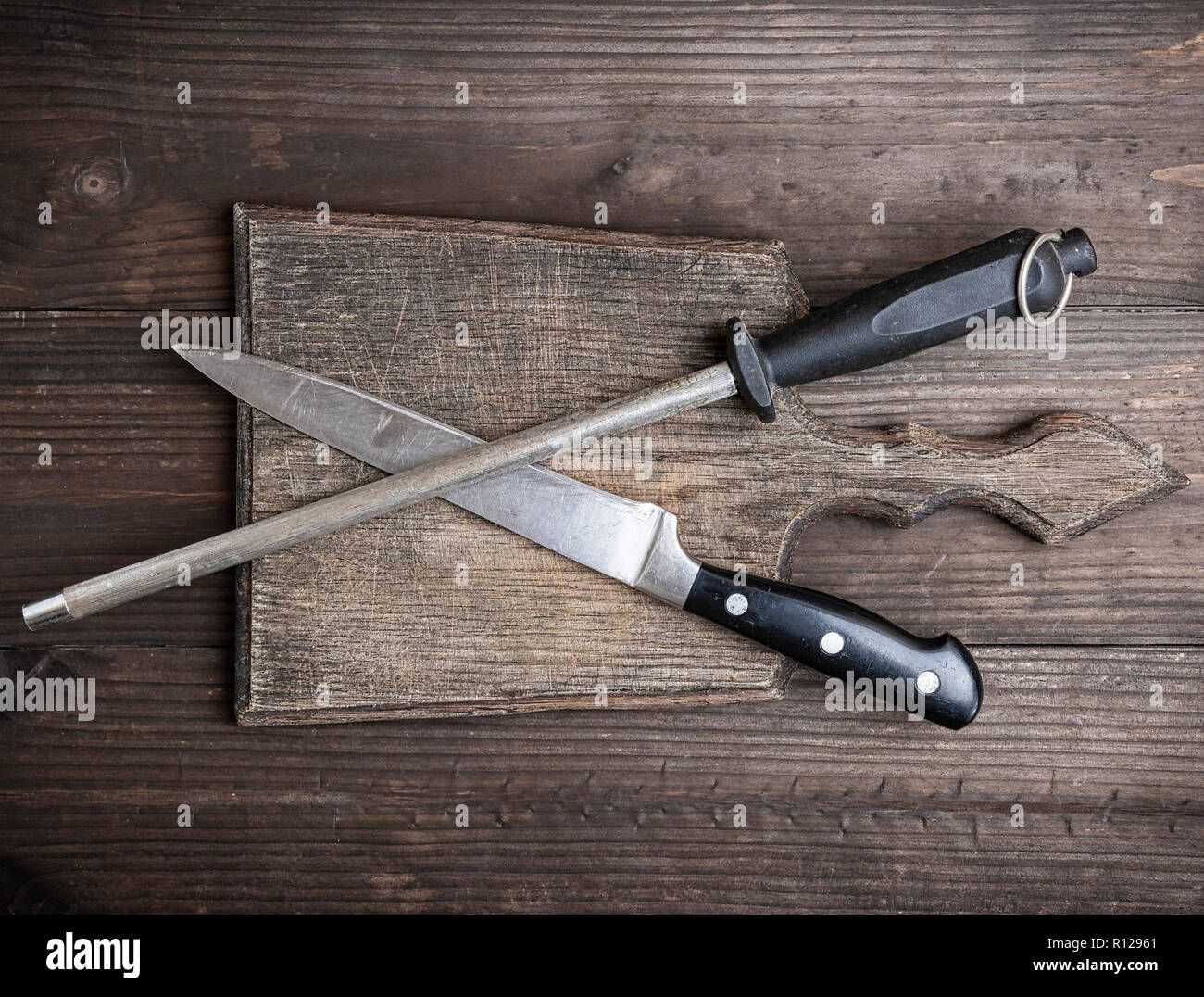 Alte braune Holz Schneidebrett und Messer mit Schärfen auf der Tabelle, Ansicht von oben Stockfoto