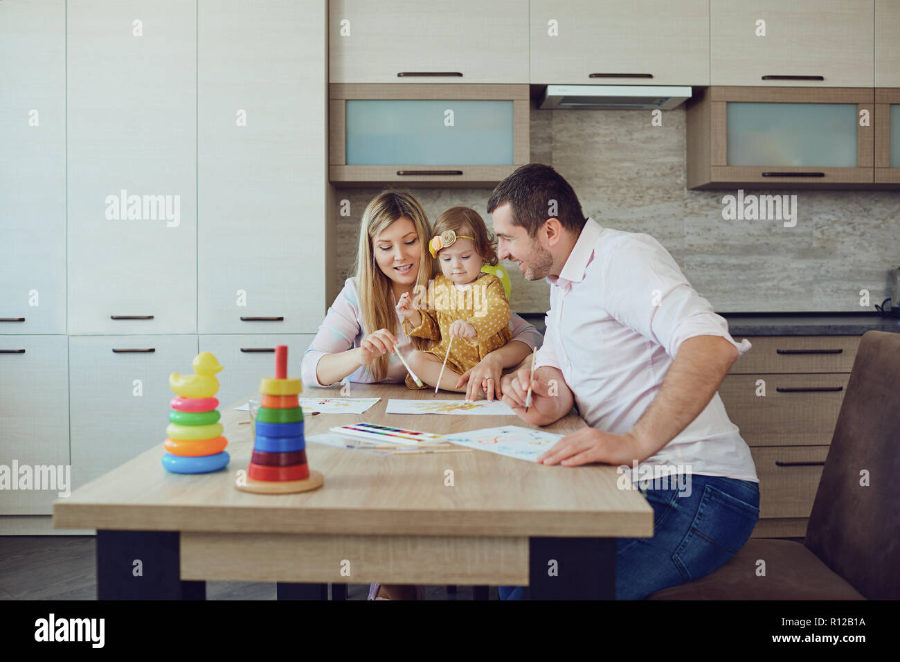 Mutter, Vater und Kind zeichnen zusammen am Tisch. Stockfoto