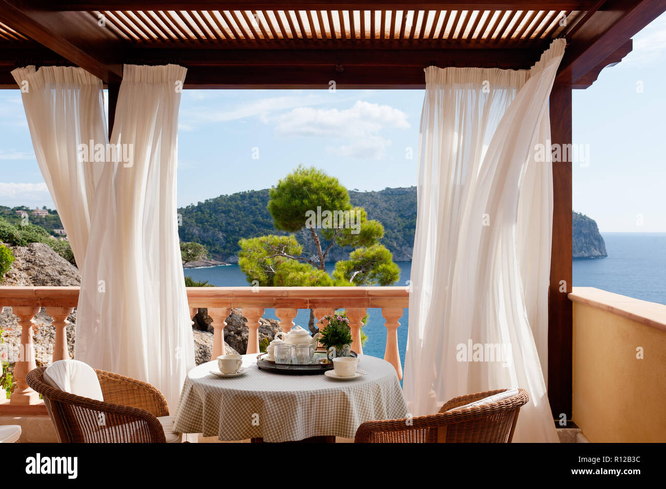 Tisch und Stühle auf dem Balkon mit Vorhängen Stockfoto