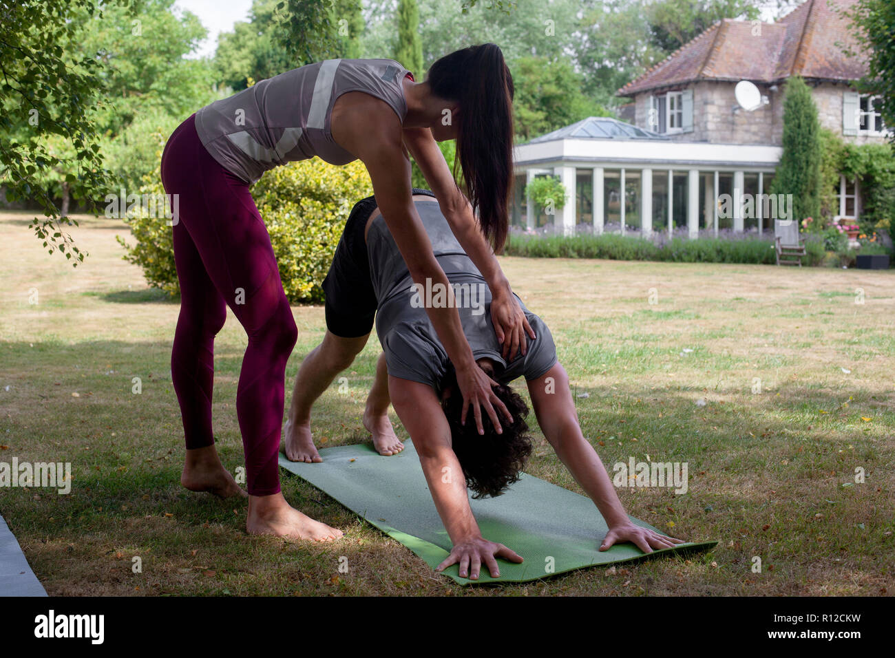 Weibliche Yoga Lehrer unterrichten junger Mann, Yoga im Garten, in den